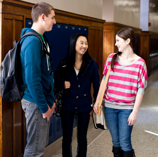 13 to 18 year olds standing against school lockers having a conversation.