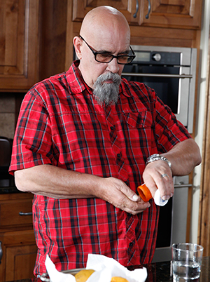 Man taking pills in kitchen.