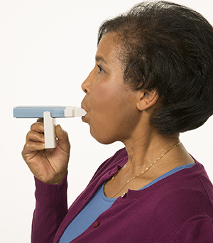 Woman using a peak flow meter.