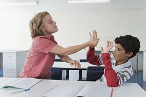 A boy bullying another boy in class.