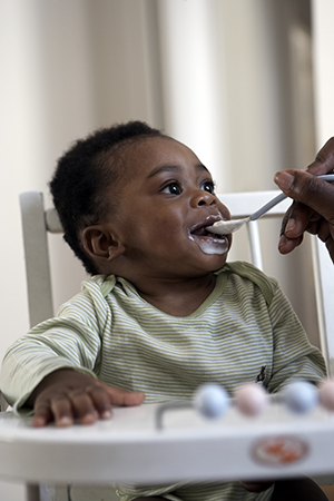 Baby being fed in high chair.