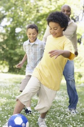 Boys playing soccer with their dad