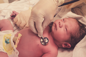 Checking newborn baby boy heart rate with a stethoscope.