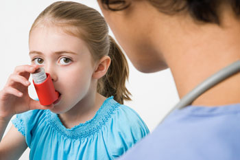 Child using an inhaler with nurse nearby