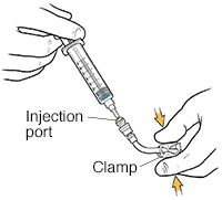 Closeup of hands pressing clamp on catheter tubing with syringe in injection port.
