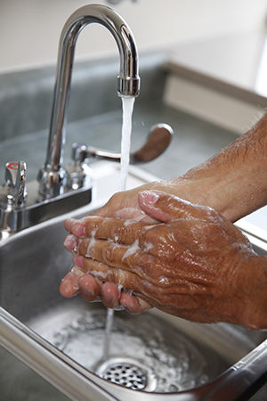 Closeup of man washing hands in sink.