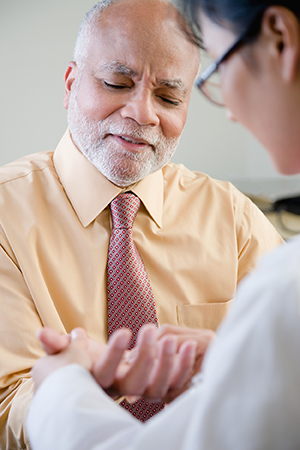 Doctor examining man’s hand.