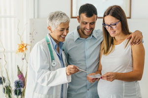 Doctor having conversation with pregnant couple.