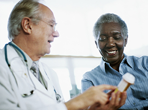 Doctor holding a prescription bottle and discussing prescription with patient.