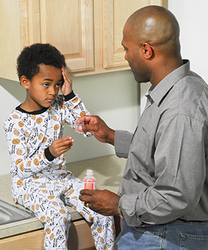 Father giving son liquid medication.