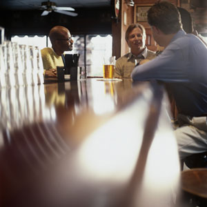 Four men sitting at a bar in a pub.