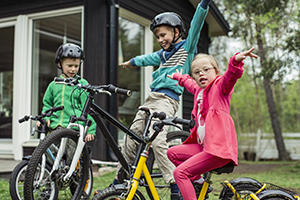 Girl riding bicycle with brothers in lawn.