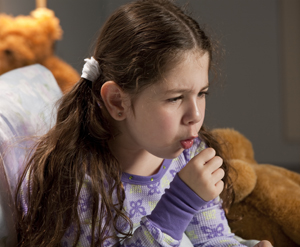 Girl sitting up in bed, coughing.