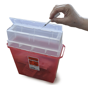 Hand disposing of syringe in sharps container.