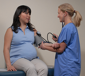 Health care provider taking pregnant woman's blood pressure.