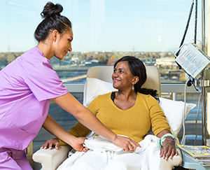 Healthcare provider caring for woman having infusion treatment.