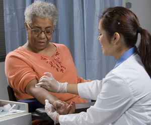 Healthcare provider drawing blood from woman's arm.