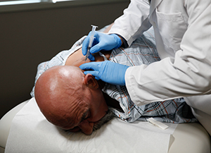 Healthcare provider giving man injection in back of neck.