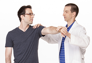 Healthcare provider helping man do shoulder exercise.