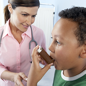 Healthcare provider instructing boy on how to use asthma inhaler.