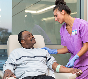 Healthcare provider preparing to take blood from woman's arm.