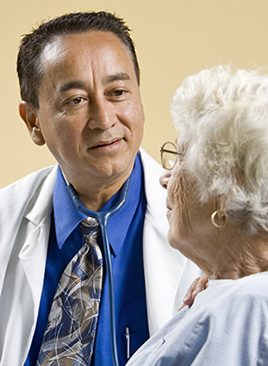 Healthcare provider talking to elderly woman in exam room