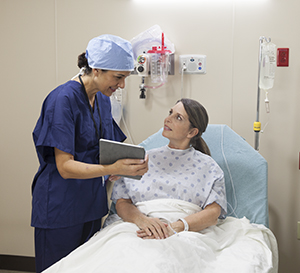 Healthcare provider talking to woman in pre-op hospital room.