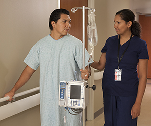 Healthcare provider walking with man in hospital hallway.