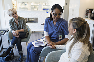 Healthcare provider talking to child, with woman looking on.