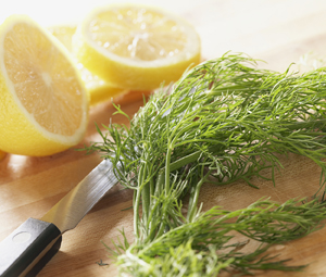 Lemons and fresh herbs on cutting board with knife.