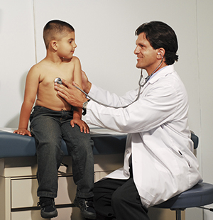 Healthcare provider listening to boy's chest with stethoscope.