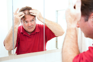 Man checking for thinning hair in the mirror.