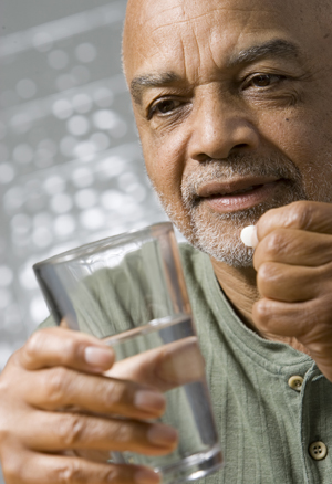 Man holding glass of water, preparing to take pill.