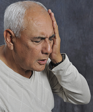 Man holding hand to head, expressing pain.