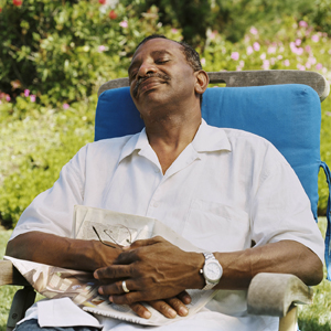 Man in chair outside, relaxing with eyes closed.