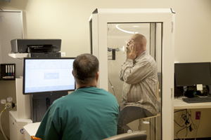 Man pinching nose shut and breathing into spirometer in mouth. Healthcare provider is monitoring test.