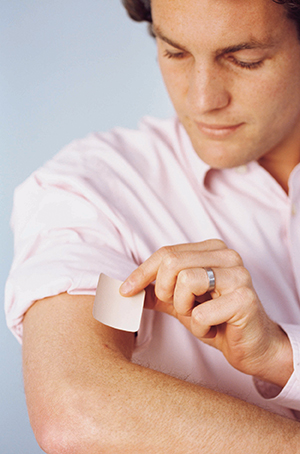 Man placing nicotine patch on arm.