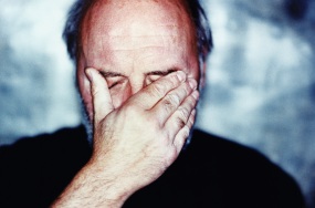 Man pressing his hand against his forehead and eyes