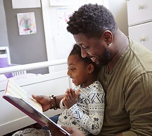 Man reading book to child at bedtime.