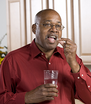 Man taking pill with glass of water.