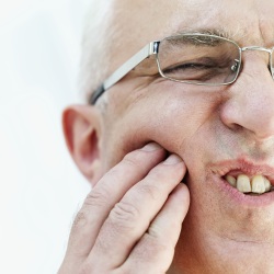 Man with expresion of pain holding his cheek