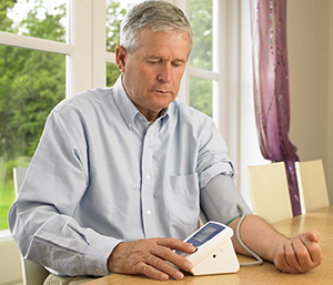 Mature man taking his blood pressure at home. 