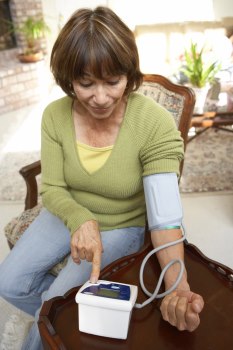 Middle aged woman taking her blood pressure with a home monitor