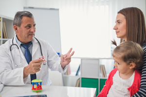 Mother and toddler girl talking to a male healthcare provider.