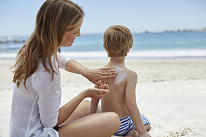 Mother applying sunscreen to son's back.