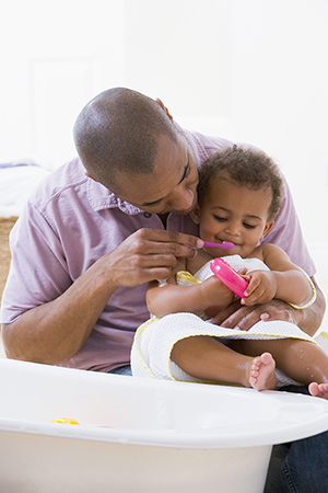 Mother cleaning babies mouth with swab.