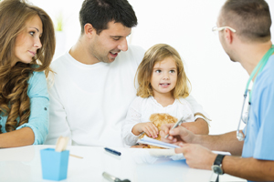 Mother, father, and girl talking to a male healthcare provider.