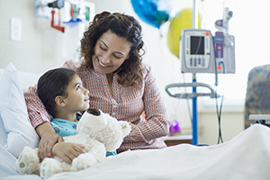 Mother holding daughter in hospital bed.