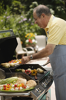 Older man cooking on a grill outdoors