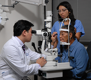 Ophthalmologist and assistant treating woman's eyes.